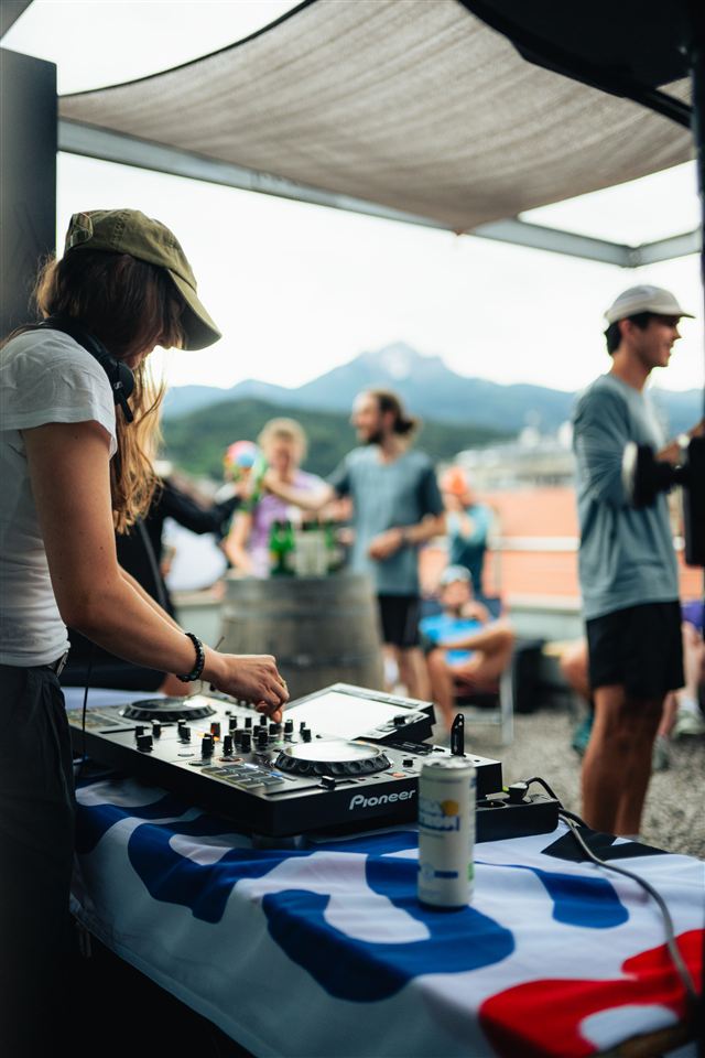 A DJ playing music as runners gather on a terrace after a community event